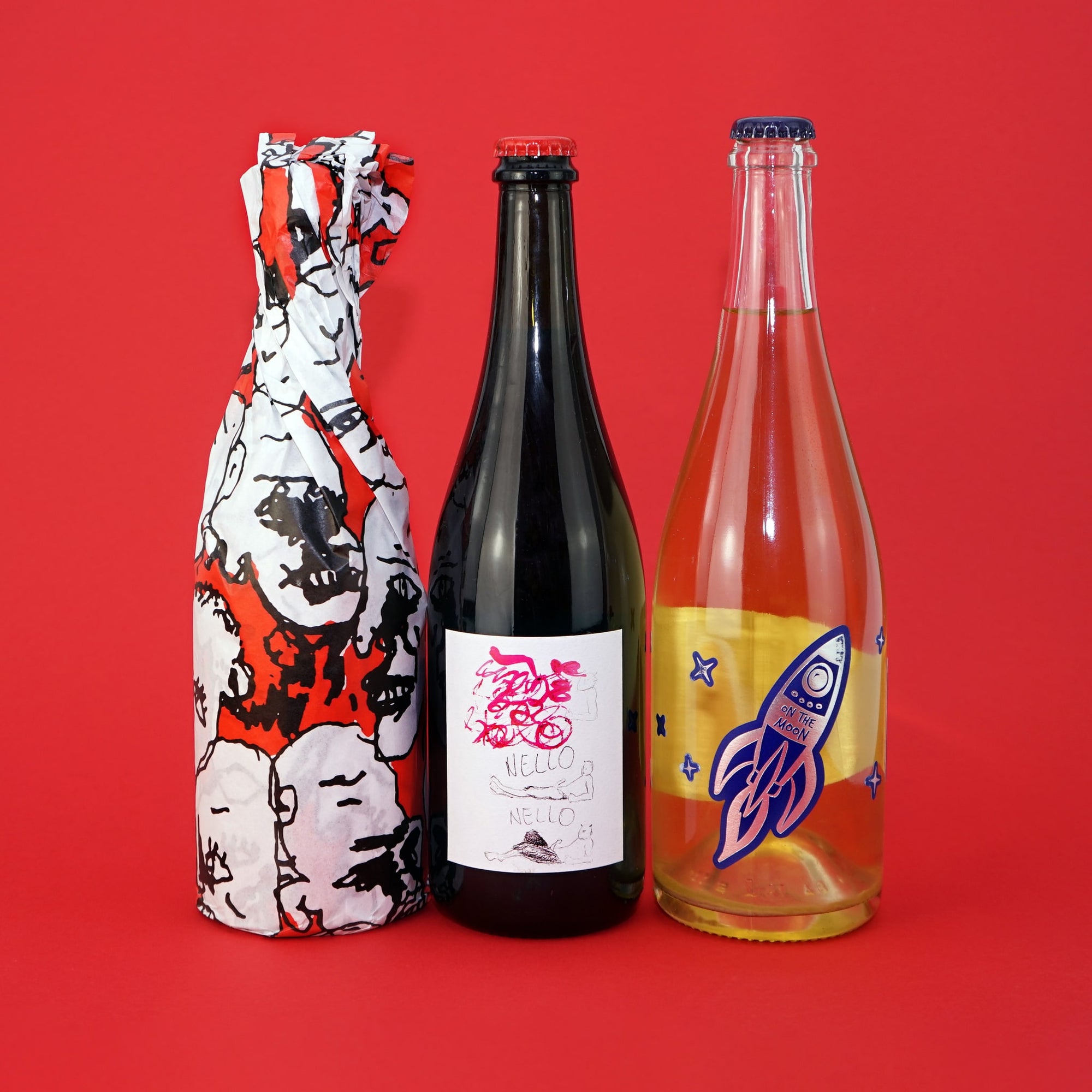 Three bottles of Pet Nat with unique designs on a red background