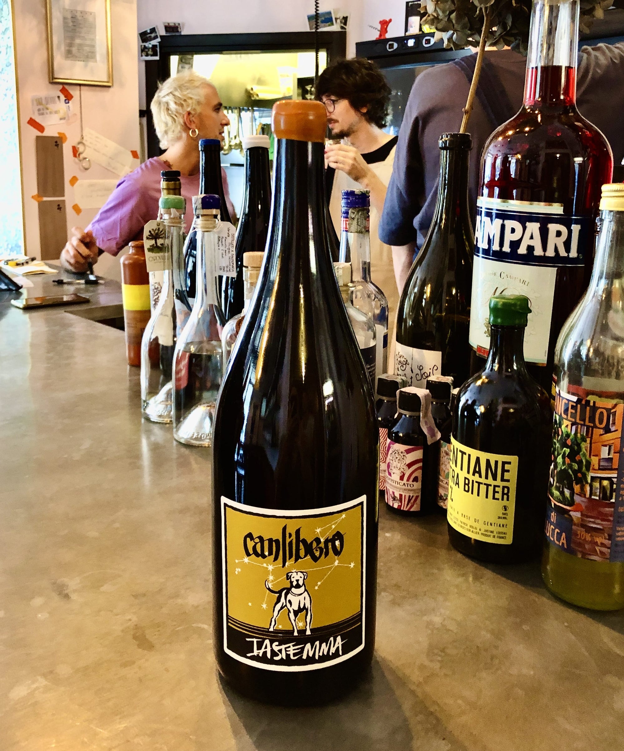 Bottles of alcohol on a bar counter with people in the background