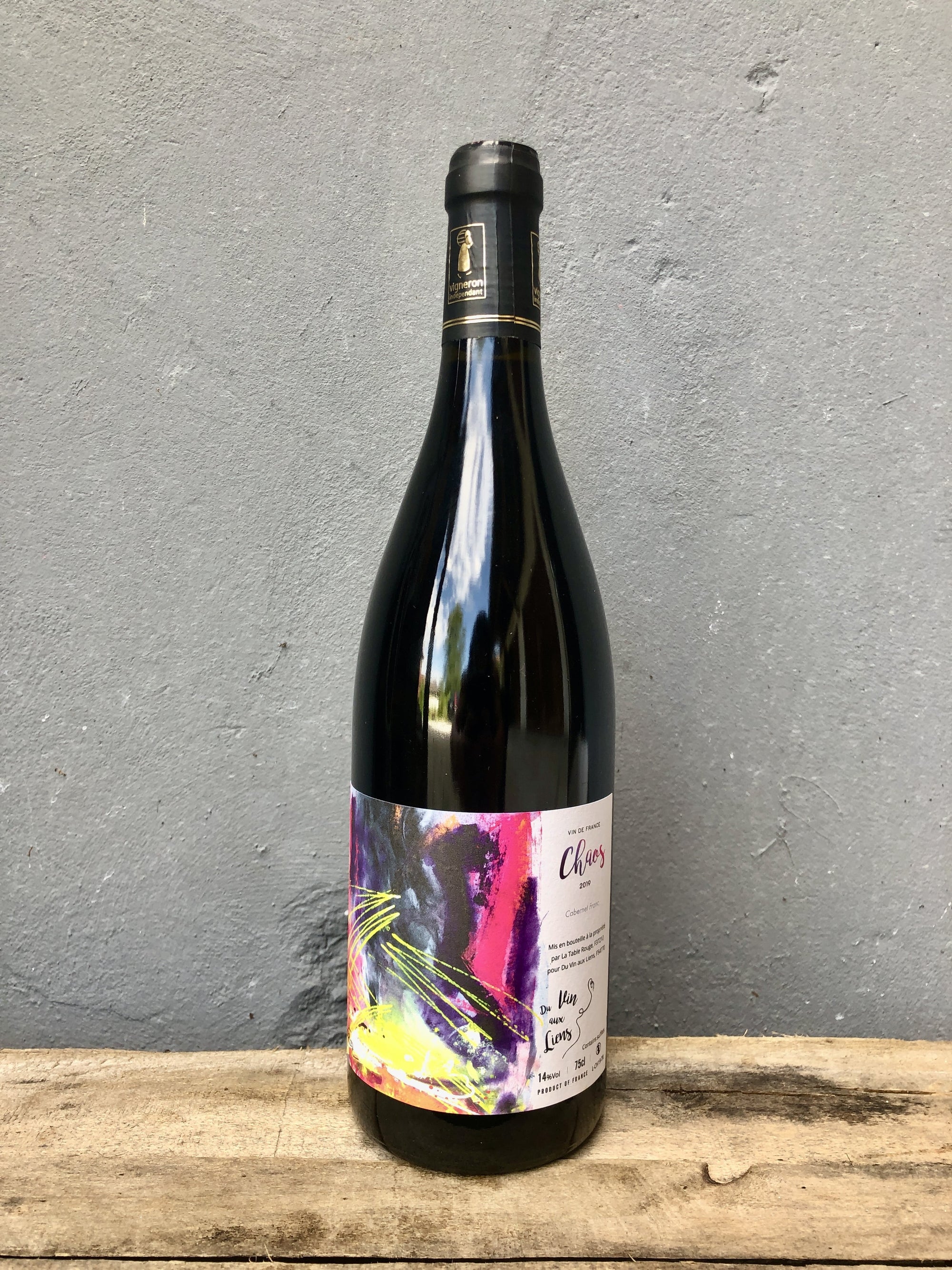 Red Wine bottle with colorful label on a wooden surface and gray background