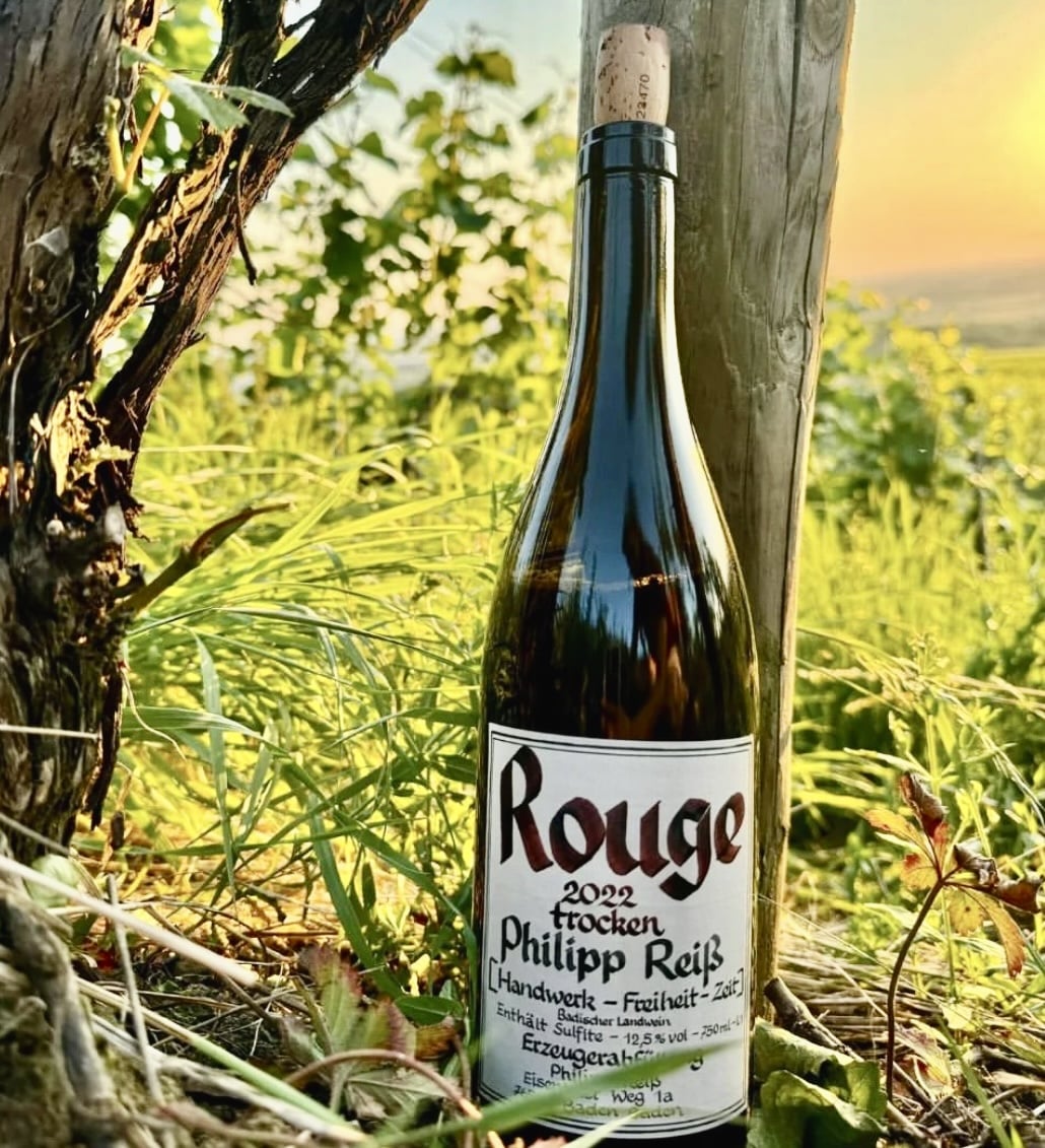 Wine bottle labeled 'Rouge' in a vineyard setting